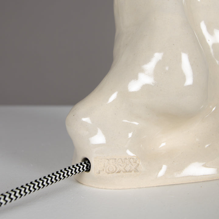 Back side of ceramic lamp with braided cord and signature detail – beige linen lampshade included. / Šviestuvo vaizdas iš nugaros su pintu laidu ir autoriniu žymėjimu – komplekte 100 % lino smėlio spalvos gaubtas.