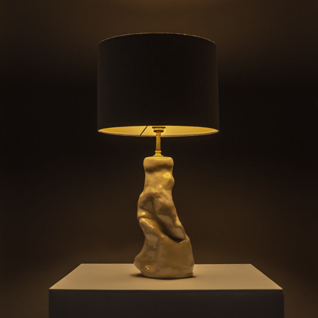 Handcrafted ceramic lamp glowing warmly in a dark space – statement lighting with a soft linen shade for moody, artistic interiors. / Rankų darbo keraminis šviestuvas su lino gaubtu šviečia jaukiai – puikus akcentas atmosferiškam interjerui.