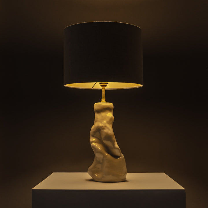 Handcrafted ceramic lamp glowing warmly in a dark space – statement lighting with a soft linen shade for moody, artistic interiors. / Rankų darbo keraminis šviestuvas su lino gaubtu šviečia jaukiai – puikus akcentas atmosferiškam interjerui.