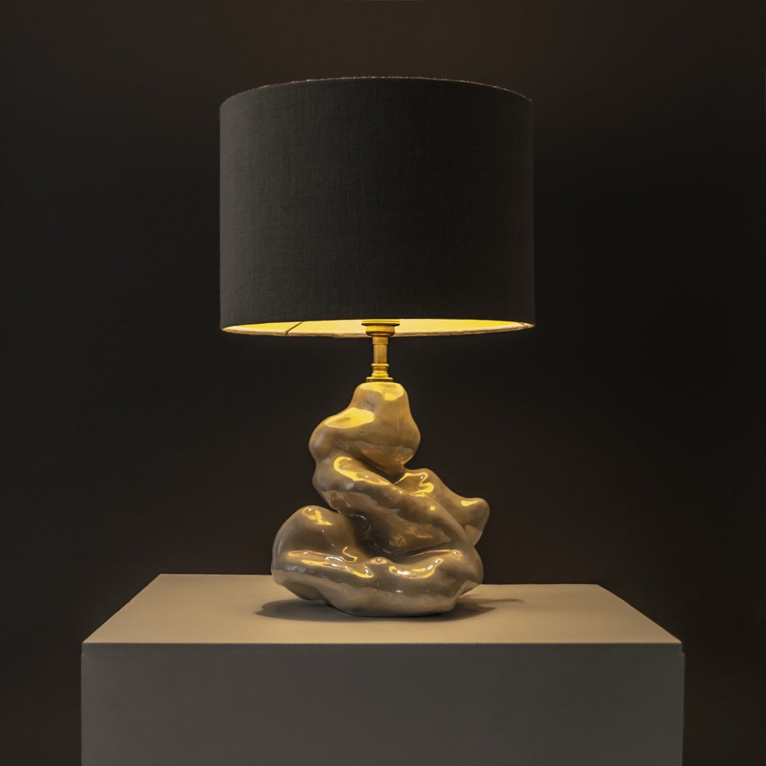 Ceramic sculptural lamp glowing in warm ambient light – functional art piece for cozy home settings. / Keraminis skulptūrinis šviestuvas skleidžia šiltą šviesą – funkcionalus meno kūrinys jaukiems namams.