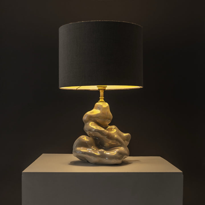 Ceramic sculptural lamp glowing in warm ambient light – functional art piece for cozy home settings. / Keraminis skulptūrinis šviestuvas skleidžia šiltą šviesą – funkcionalus meno kūrinys jaukiems namams.