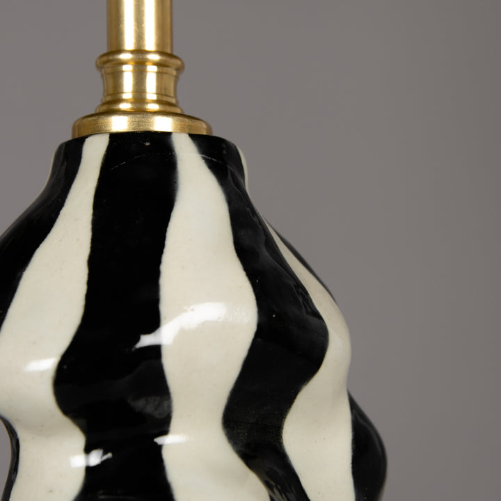 Close-up of sculptural ceramic base – bold black and white texture on modern handmade stoneware lamp. / Skulptūrinio šviestuvo pagrindo stambus planas – išraiškingas juodai baltas paviršius, sukurtas iš akmens masės.