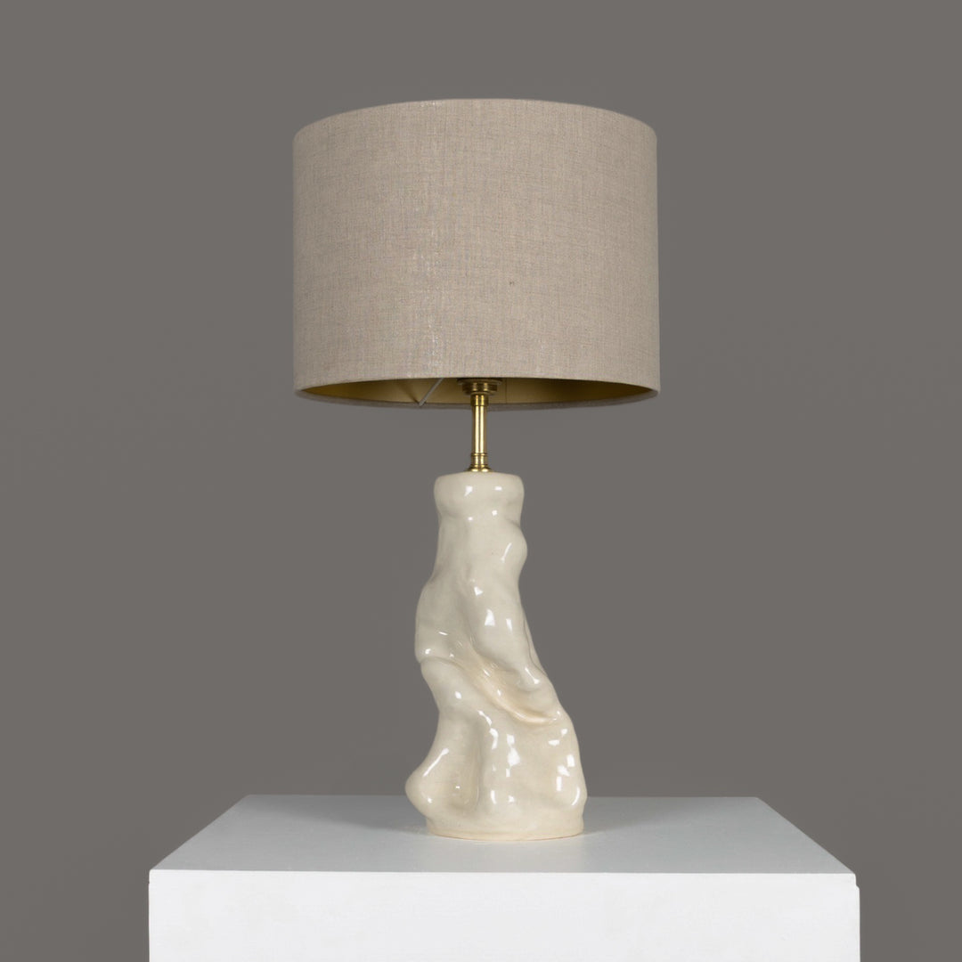 Minimalist sculptural table lamp with organic stoneware base and natural beige linen lampshade – perfect for Scandinavian-inspired interiors. / Minimalistinis skulptūrinis stalinis šviestuvas su organišku akmens masės pagrindu ir 100 % lino smėlio spalvos gaubtu – skandinaviškam stiliui.