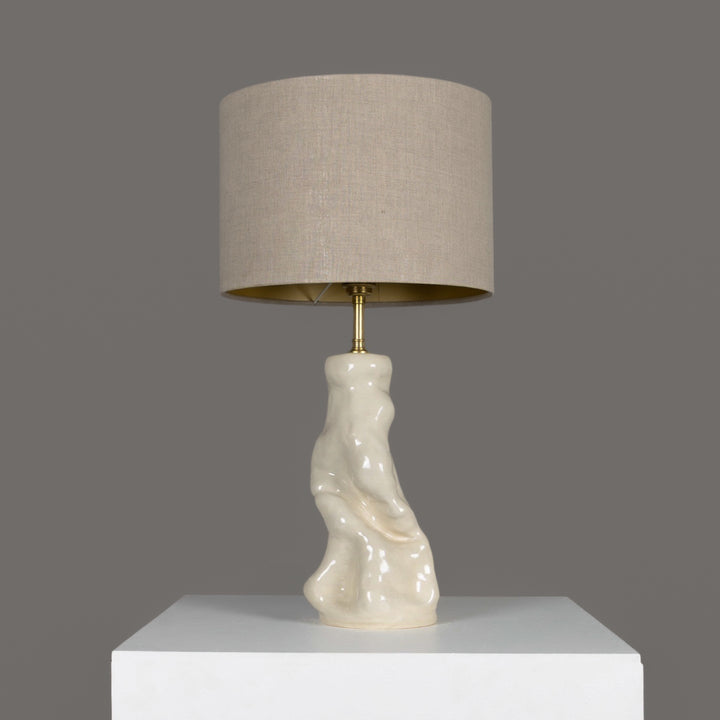 Minimalist sculptural table lamp with organic stoneware base and natural beige linen lampshade – perfect for Scandinavian-inspired interiors. / Minimalistinis skulptūrinis stalinis šviestuvas su organišku akmens masės pagrindu ir 100 % lino smėlio spalvos gaubtu – skandinaviškam stiliui.