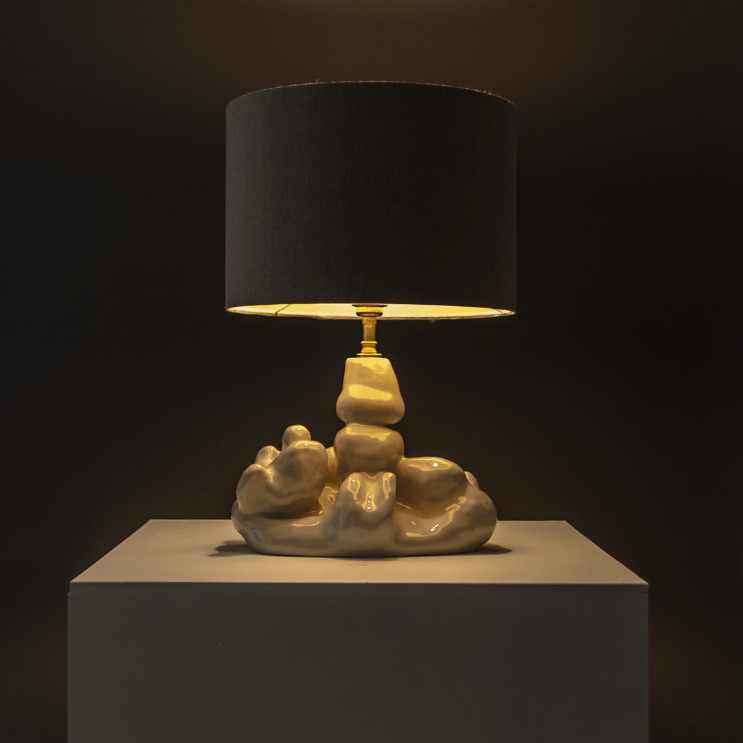 Warm light from handcrafted stoneware lamp – sculptural lighting for evening ambiance, styled with natural linen shade. / Šiltai šviečiantis rankų darbo akmens masės šviestuvas su natūraliu lino gaubtu – jaukiems vakarams