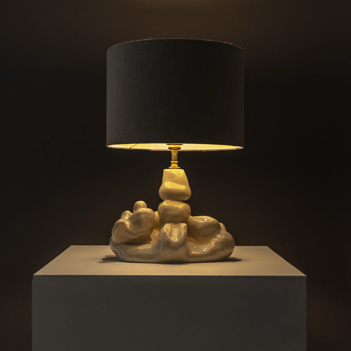 Warm light from handcrafted stoneware lamp – sculptural lighting for evening ambiance, styled with natural linen shade. / Šiltai šviečiantis rankų darbo akmens masės šviestuvas su natūraliu lino gaubtu – jaukiems vakarams