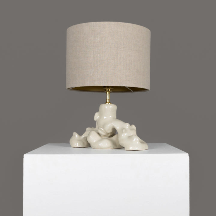 Profile view of sculptural stoneware table lamp – glazed finish, linen lampshade included. / Skulptūrinio akmens masės stalinio šviestuvo šoninis vaizdas – blizgi glazūra, komplektuojamas su lino gaubtu