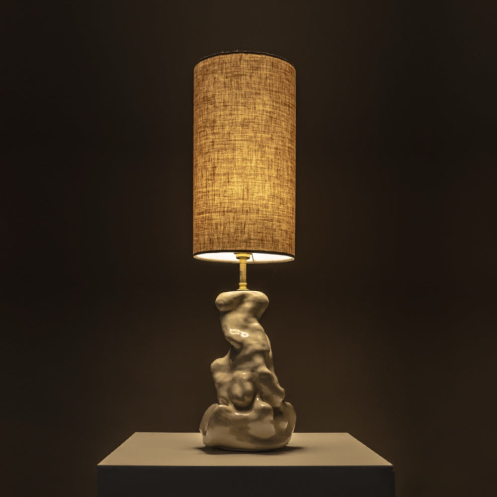 Handmade ceramic table lamp softly glowing in a dark room – modern sculptural lighting for cozy home corners. / Rankų darbo keramikinis šviestuvas jaukiai šviečia – modernus skulptūrinis apšvietimas namų kampeliams.