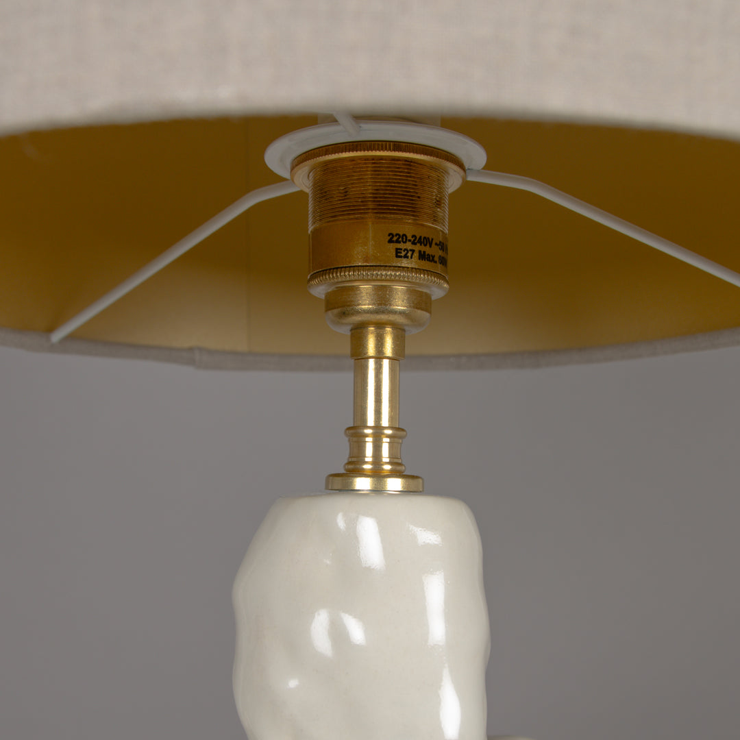 Close-up of the brass structure holding a 100% linen beige lampshade – premium handmade lighting detail. / Žalvarinė struktūra ir 100 % lino gaubtas – kokybiška rankų darbo šviestuvo detalė.