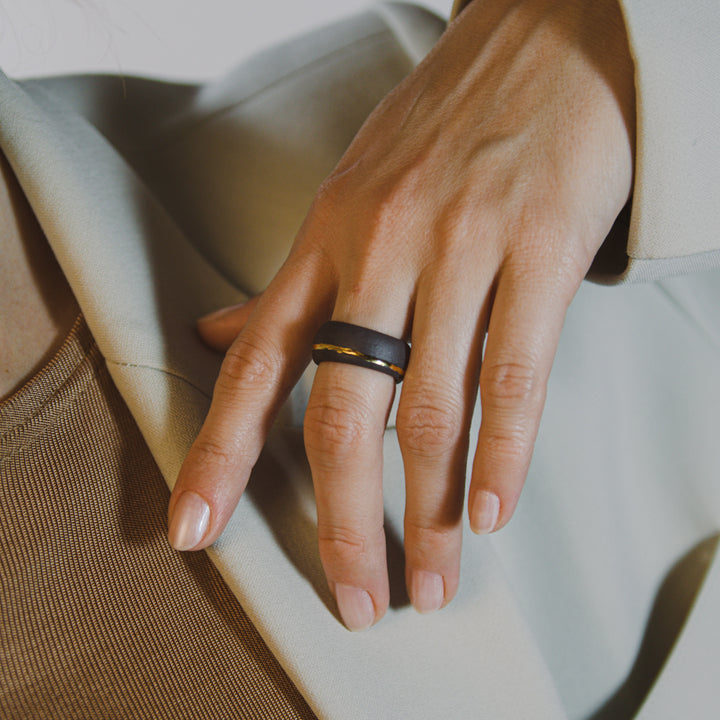 Juodas dizainerio žiedas iš porceliano ant moters rankos – modernus ir stilingas keramikinis žiedas. Rankų darbo papuošalas, sukurtas Lietuvos kūrėjų FreakyFoxx, puikiai dera prie minimalistinio ar prabangaus įvaizdžio