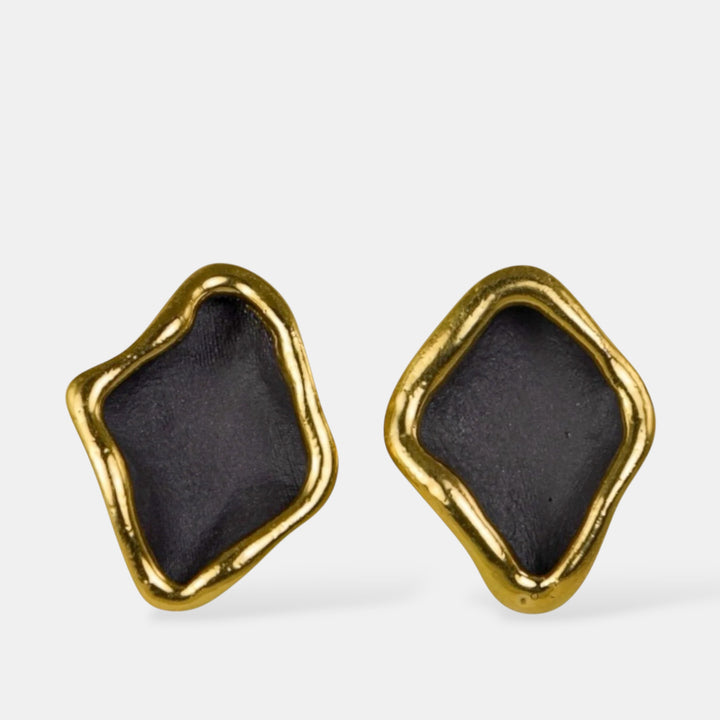 Pair of porcelain earrings with gold frames and black centers by freakyfoxx on a white background