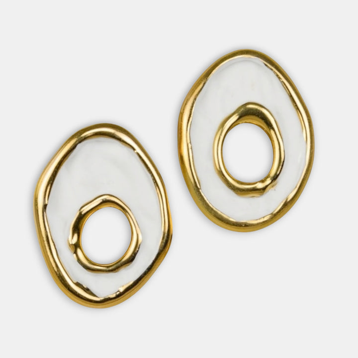 Gold and white spiral earrings on a light gray background