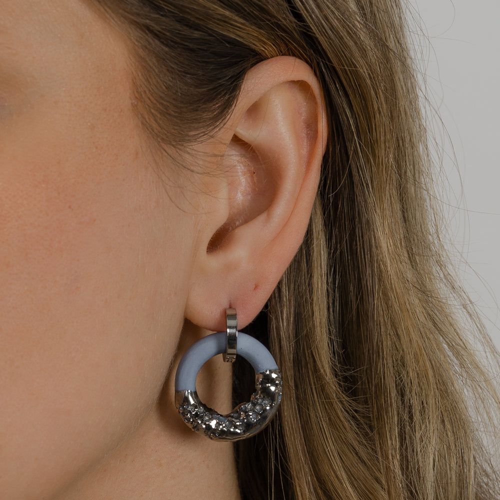 Close-up of an ear wearing a silver and blue hoop earring.