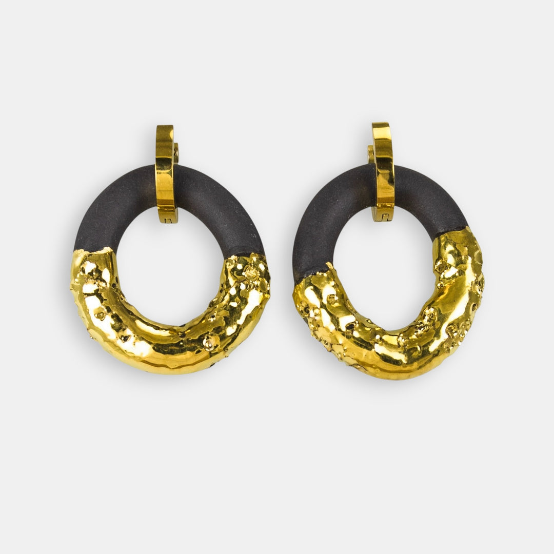 Pair of gold and black hoop earrings with charm by freakyfoxx on a light gray background. 