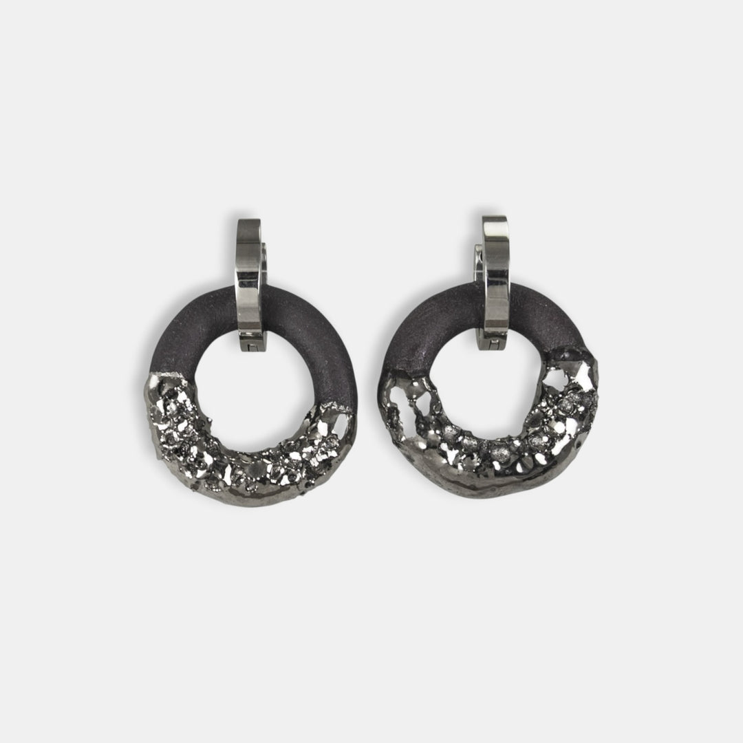 Medicininio plieno žiedinių auskarų pora su juodais akcentais baltame fone, gamintojas freakyfoxx