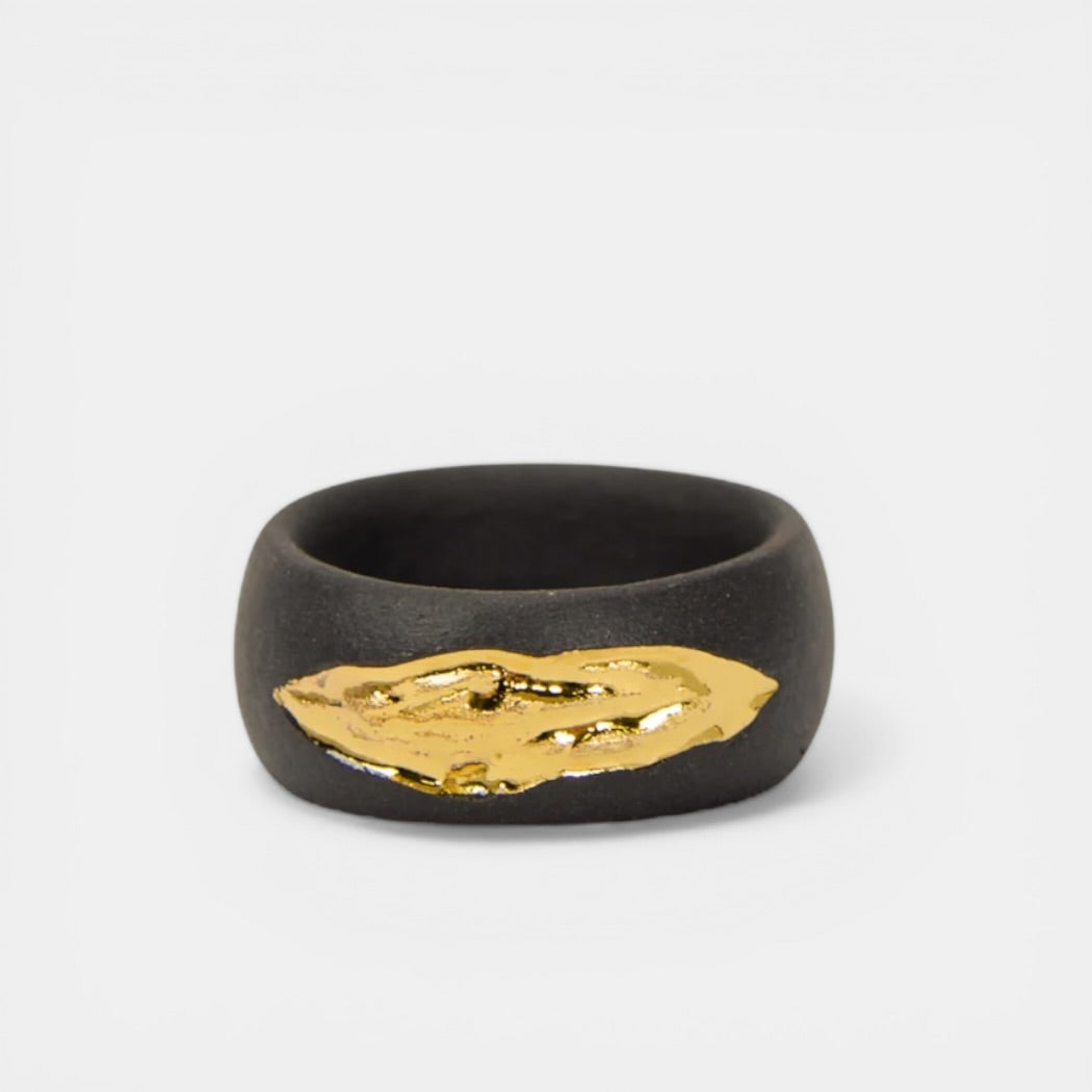 Black ring with a gold leaf design on a white background