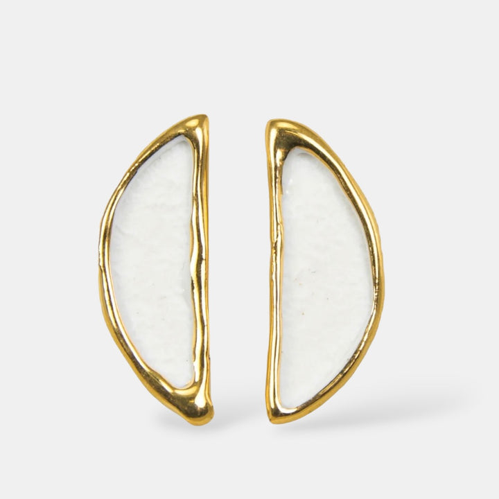 Auksiniai auskarai su baltu porcelianu šviesiai pilkame fone