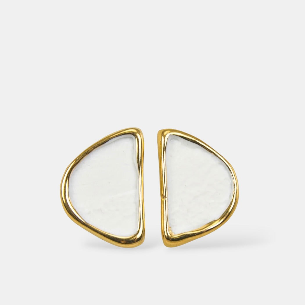 Triangular earrings with gold frames and white centers on a light gray background