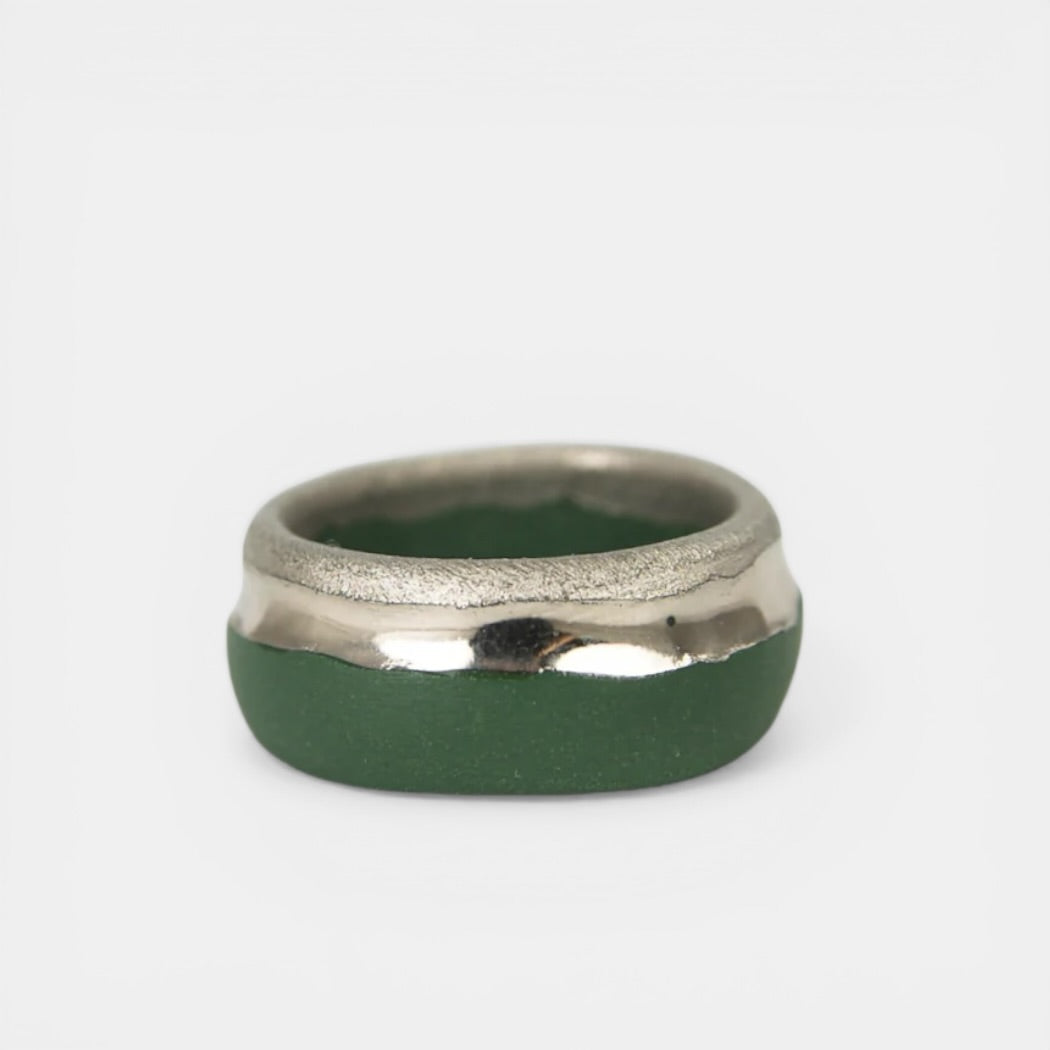 Green ring with platinum band on a light gray background