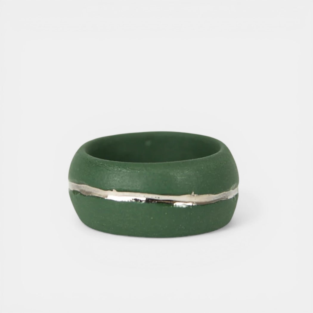 Green ring with a silver band on a white background. Porcelain