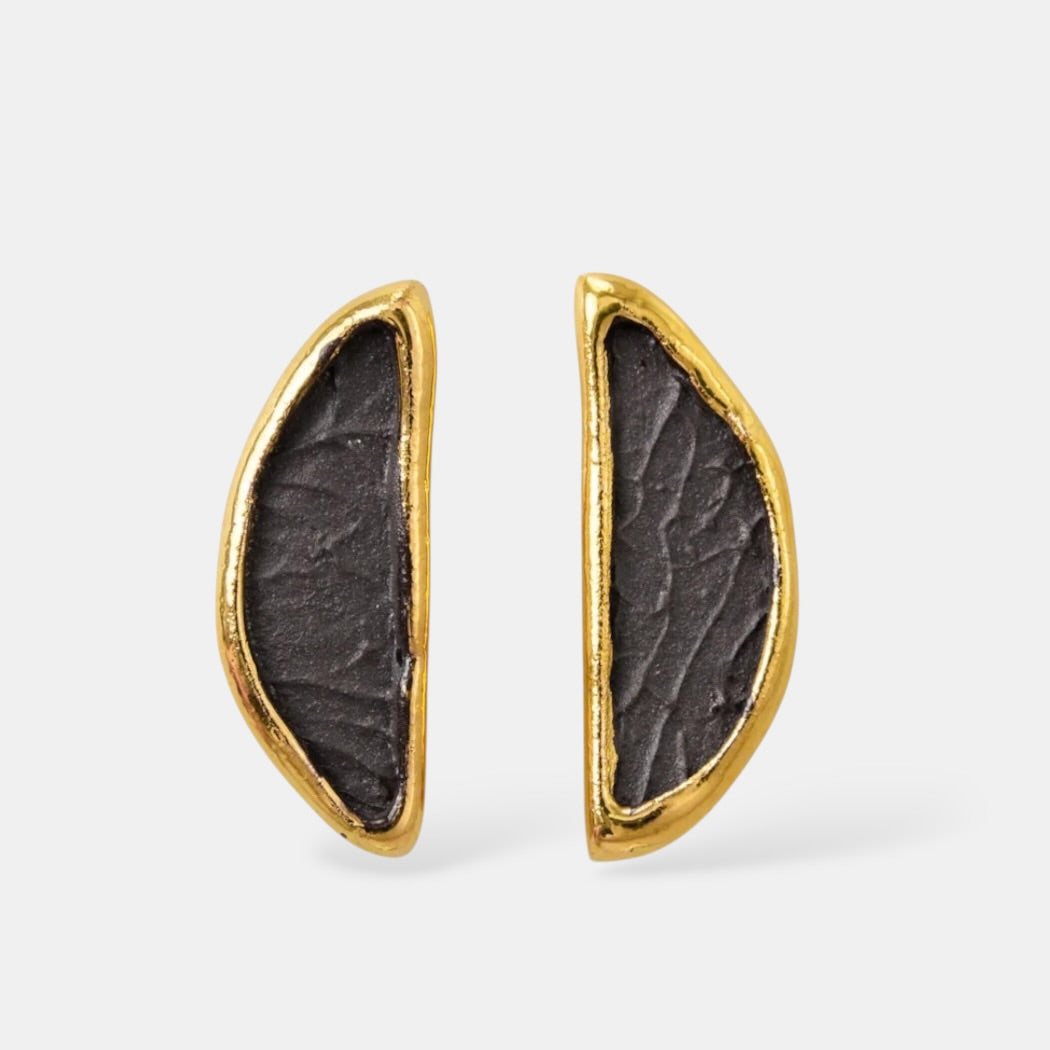 Pair of porcelain earrings with gold frames and dark stone-like centers on a white background