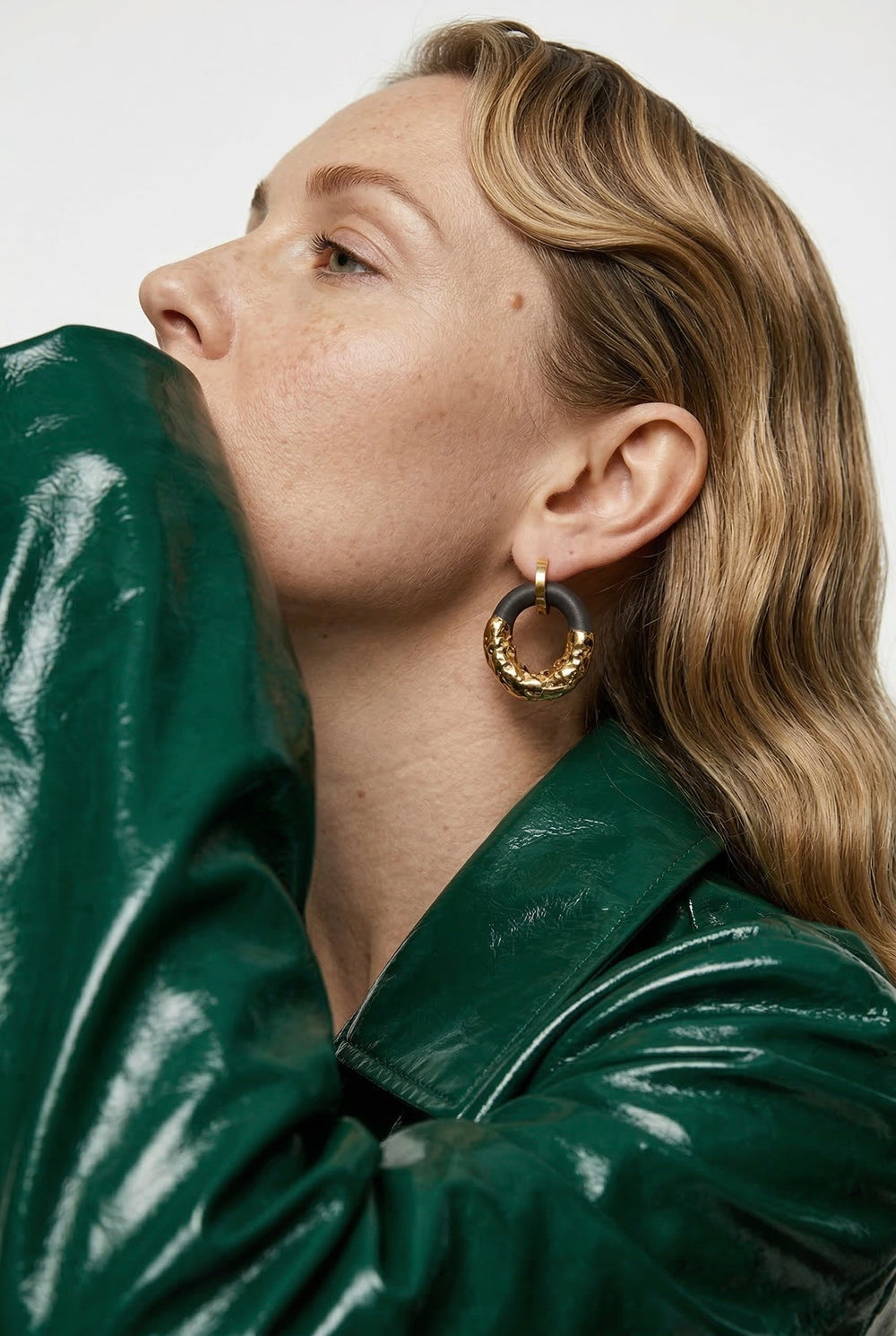 Woman wearing a green jacket and gold hoop earrings by freakyfoxx against a white background