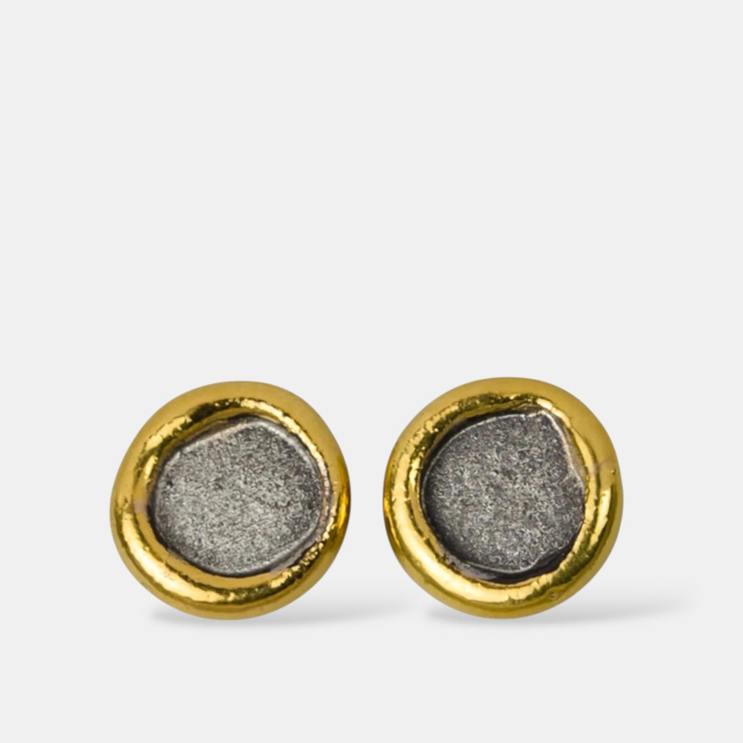 Pair of gold and silver stud earrings on a light gray background