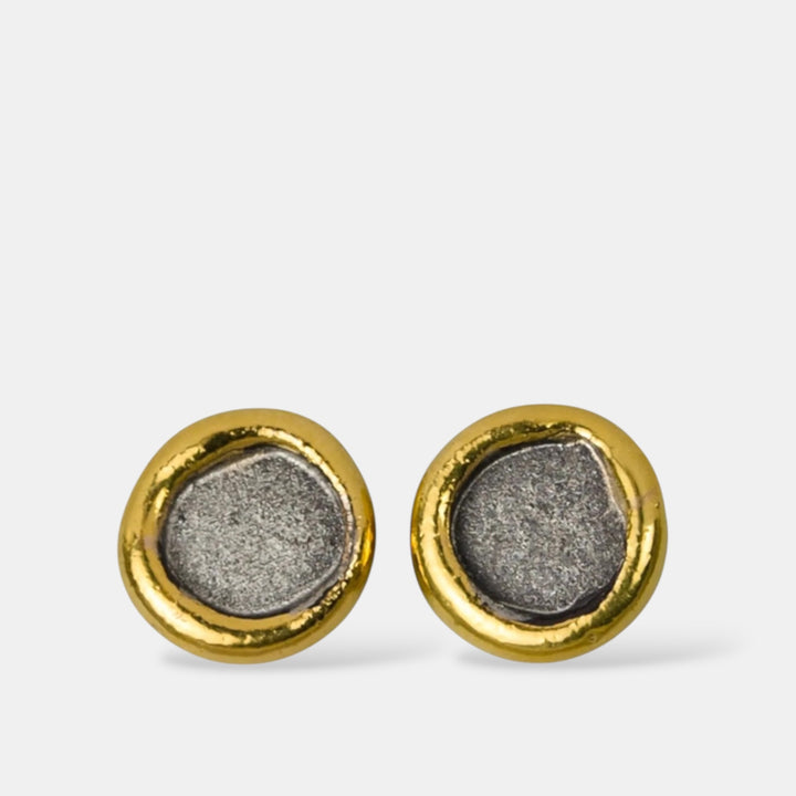 Pair of gold and silver stud earrings on a light gray background