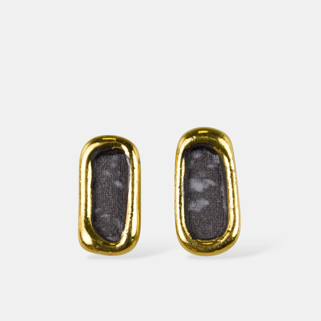 Pair of gold-framed black porcelain earrings by freakyfoxx on a white background