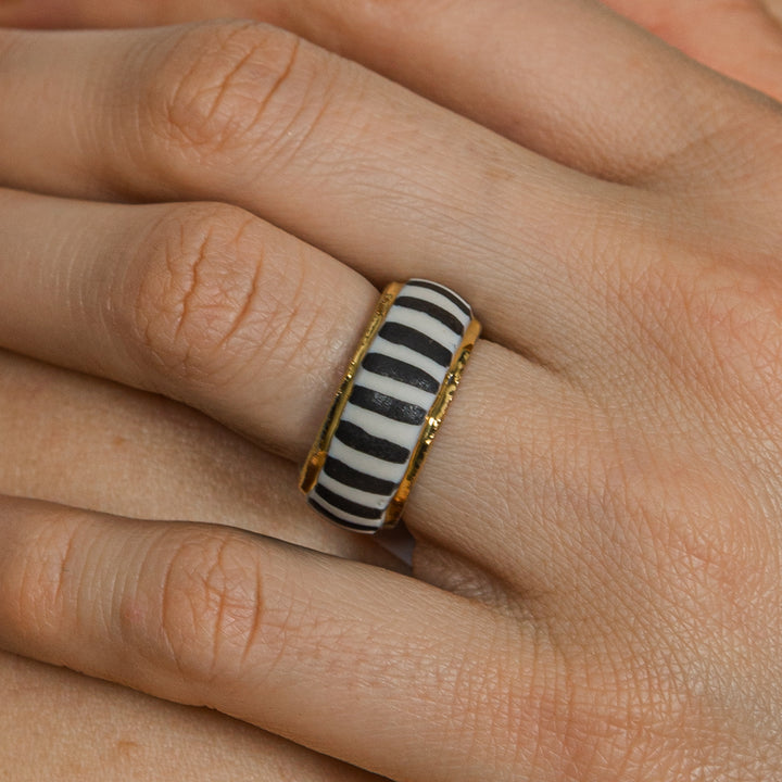 Close-up of a hand wearing a black and white striped ring with gold accents by freakyfoxx