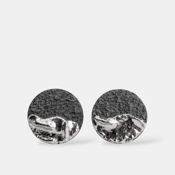 Pair of round silver earrings by freakyfoxx on a light gray background