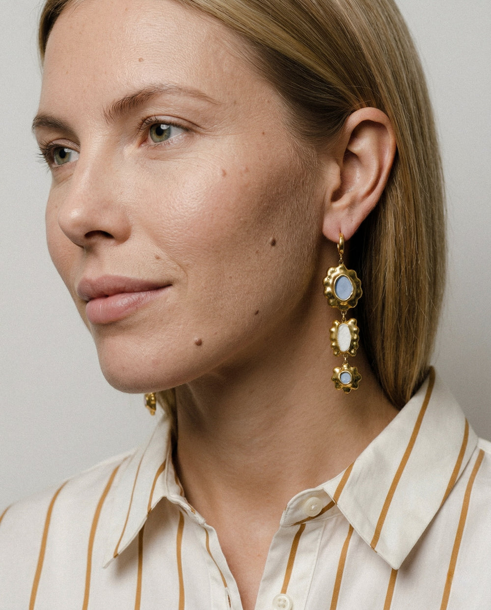 Unikalūs moteriški porcelianiniai auskarai su gėlių raštu neutraliame fone iš arti