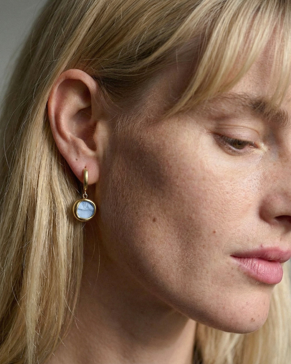 Close-up of a woman wearing porcelain earrings with gold and silver by freakyfoxx