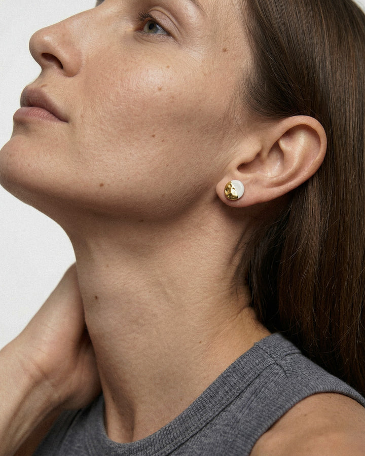 Close-up of a woman wearing white ceramic stud earrings with gold by freakyfoxx