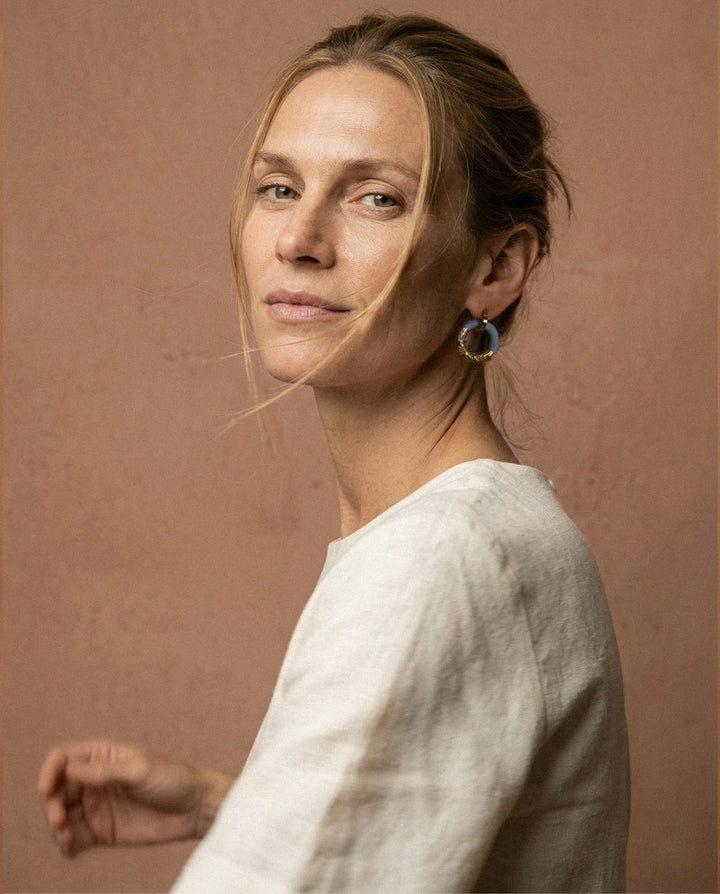 Woman wearing unique porcelain earring against a brown background