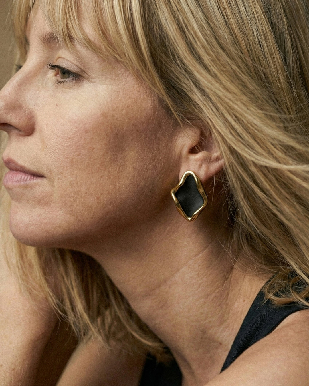 woman wearing handmade matte black porcelain earrings with gold by freakyfoxx
