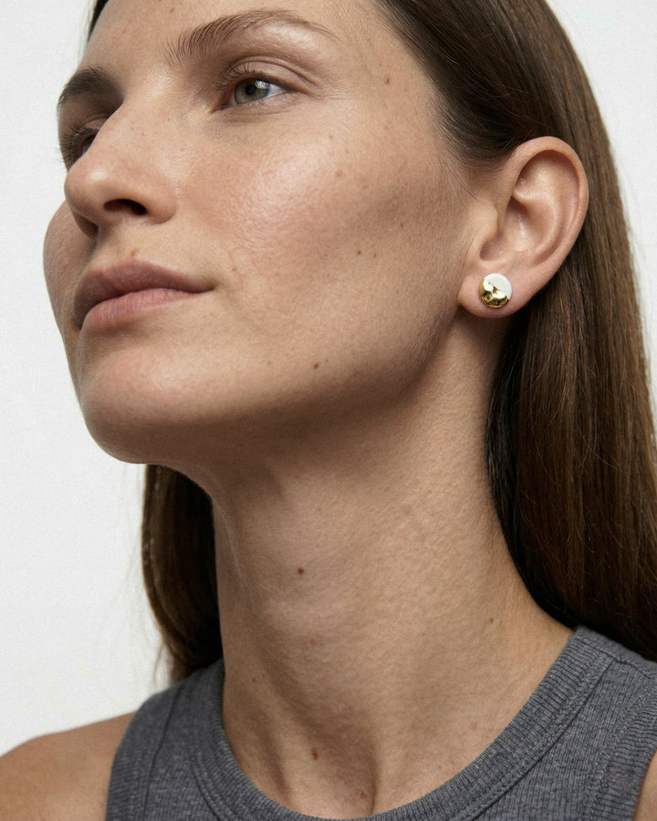 Close-up of a woman wearing handmade porcelain stud earrings with gold by freakyfoxx