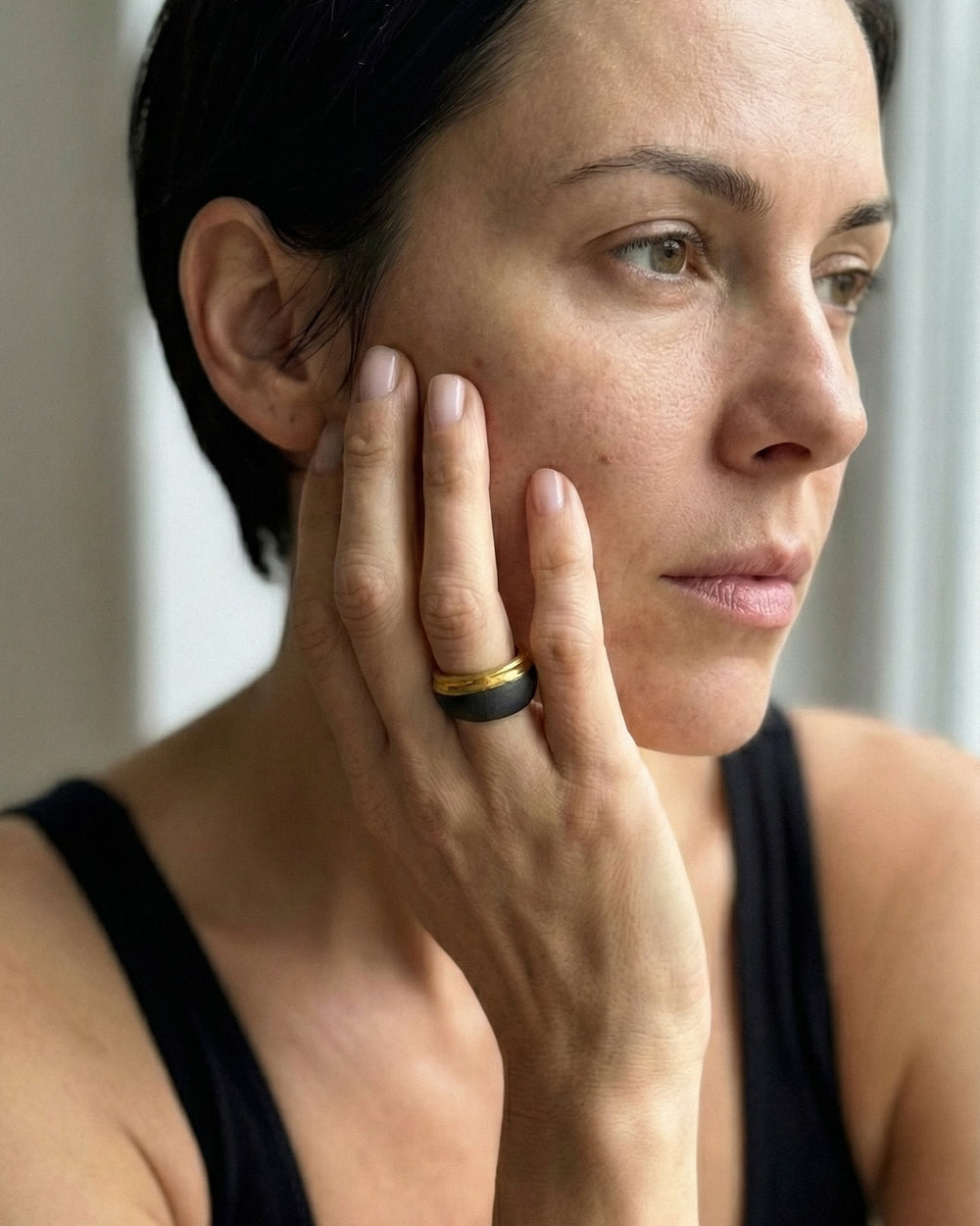 Woman with a black porcelain ring on her finger touching her face