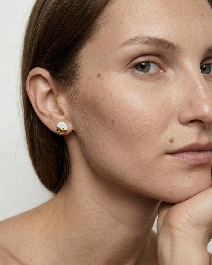 Close-up of a woman wearing white porcelain stud earrings with gold by freakyfoxx