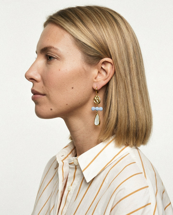 Woman wearing ceramic earrings with a neutral background