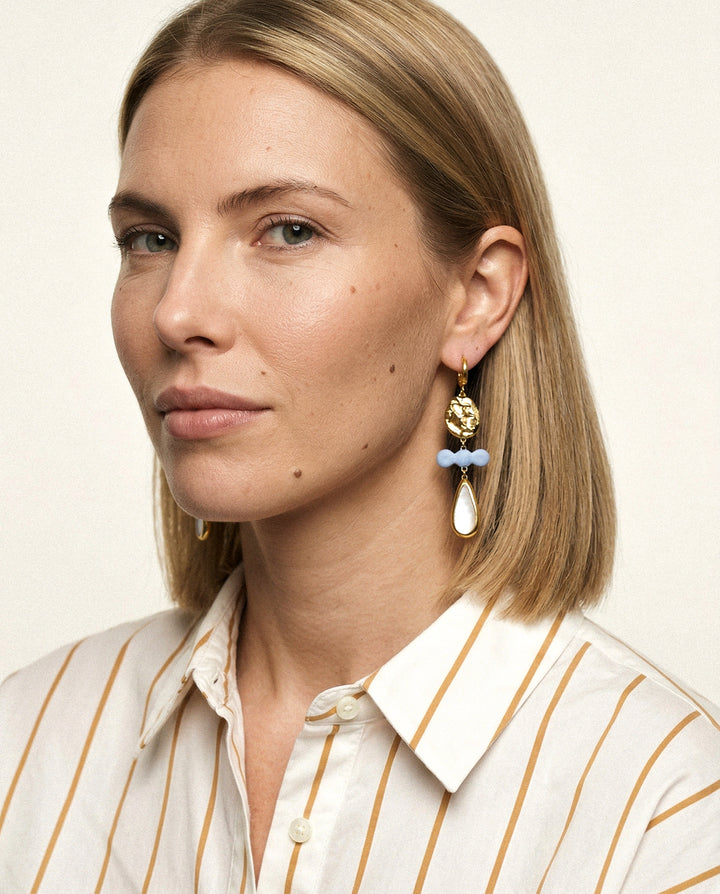 Woman wearing one of a kind porcelain earrings with blue and white accents by freakyfoxx
