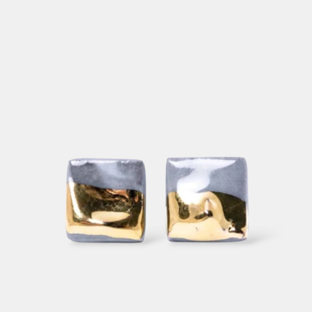 Gold and silver square stud earrings on a light gray background