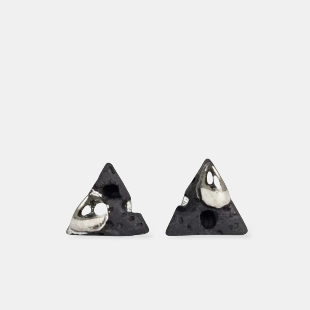 Pair of triangular earrings with metallic centers on a light gray background