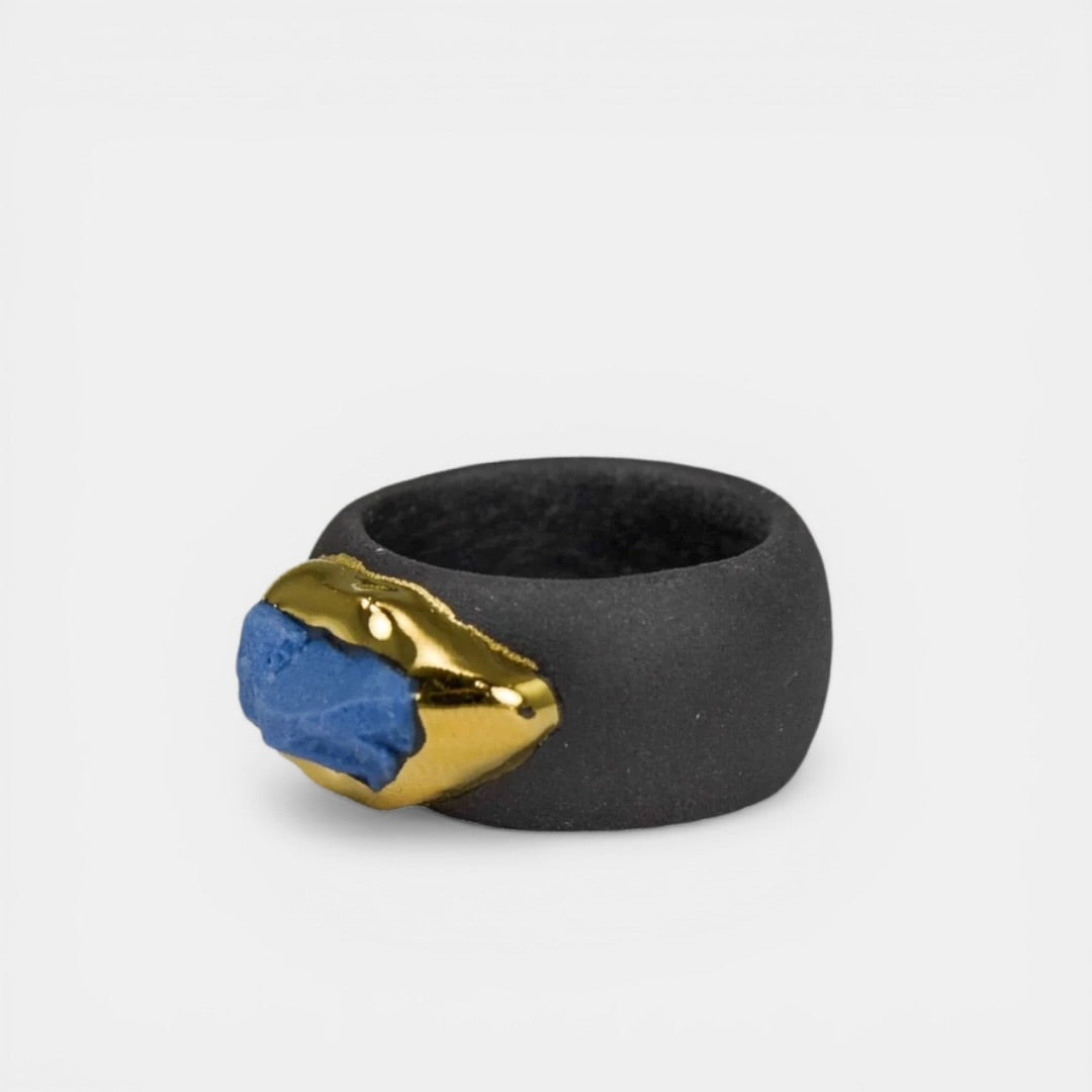 Black ring with gold and blue accent on a light gray background