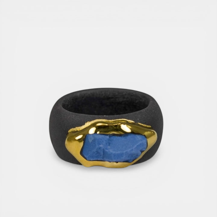 Black ring with gold and blue accents on a light gray background