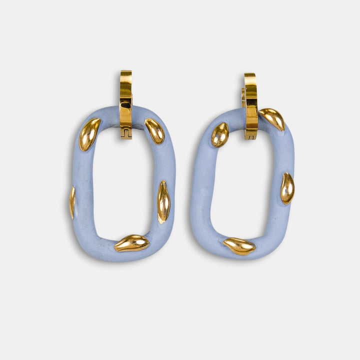 Pora unikalių šviesiai mėlynų lengvų žiedinių auskarų su auksiniais akcentais baltame fone