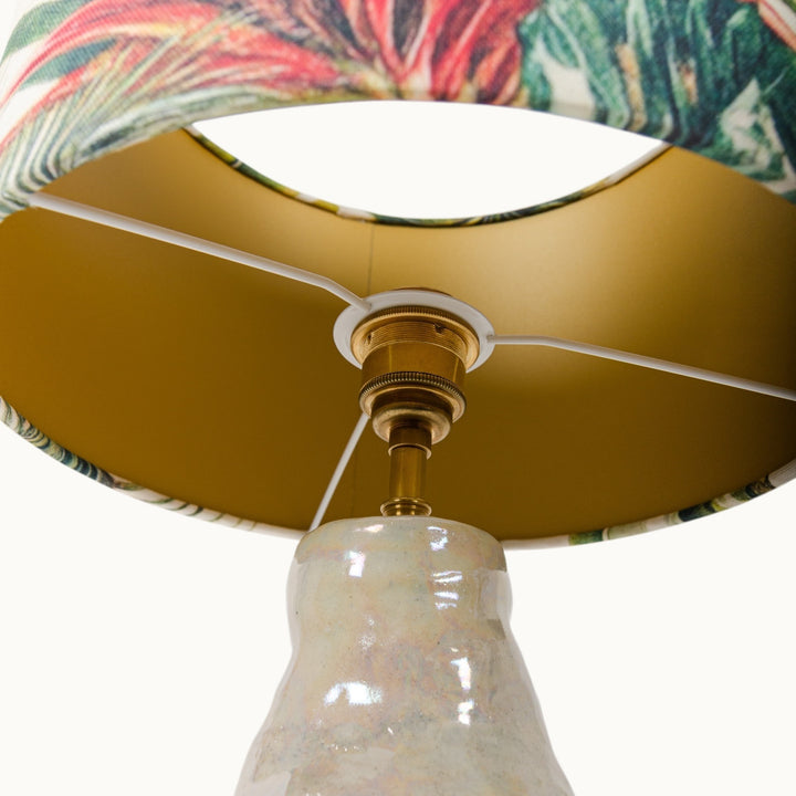 Underside view of the lampshade, revealing its luxurious gold interior and brass fittings.
Šviestuvo gaubto vidinė pusė, atskleidžianti prabangų auksu dengto paviršiaus vidų ir žalvarines jungtis.