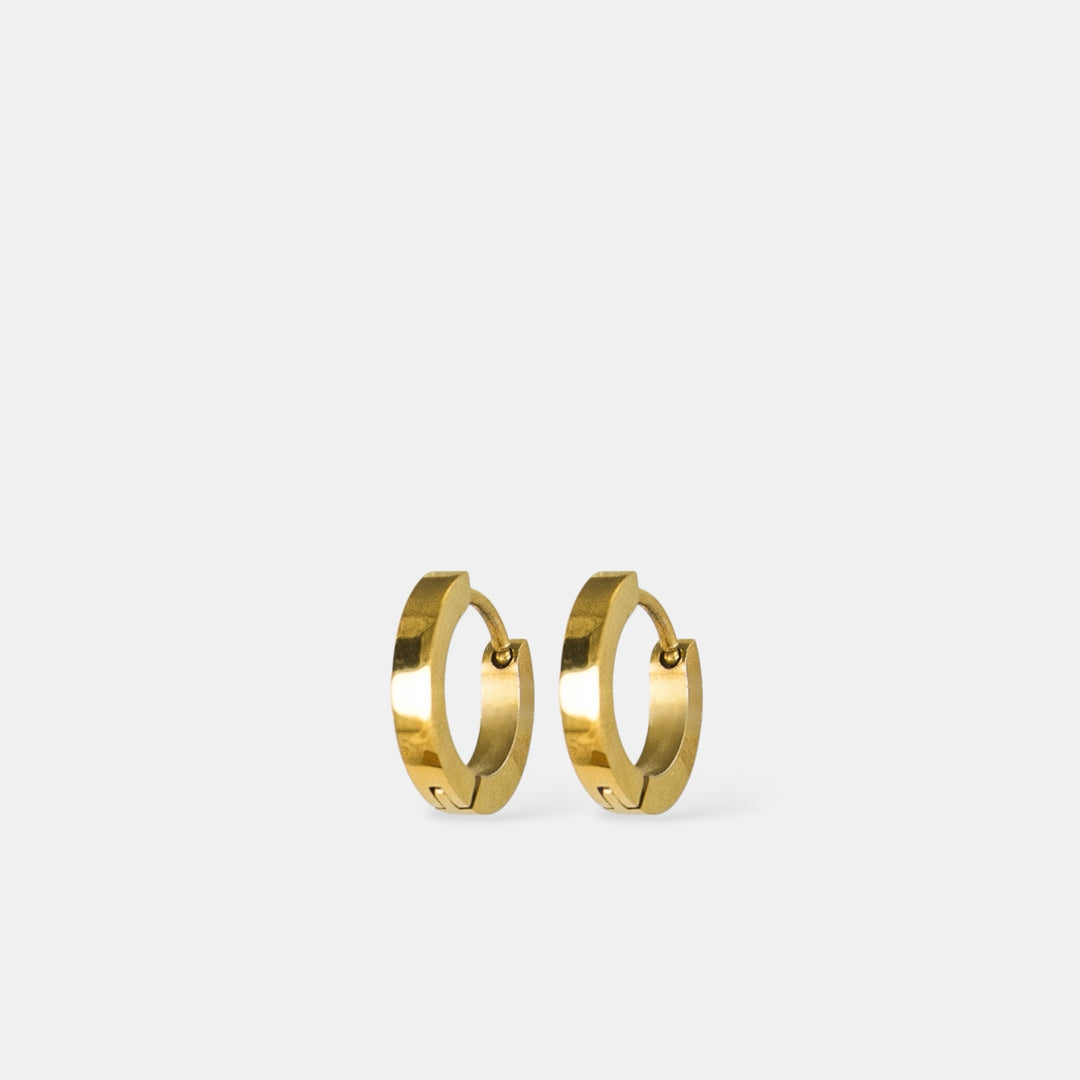 Auksiniai žiediniai auskarai šviesiai pilkame fone