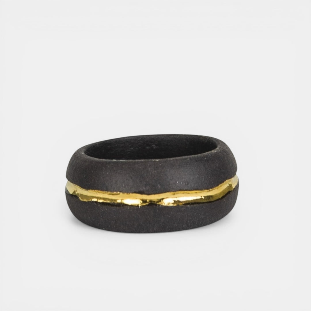 Black porcelain  ring with a gold accent on a light gray background. Juodas porceliano žiedas