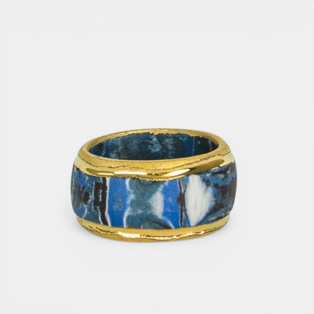 Ring with blue marbled design and gold trim on a white background